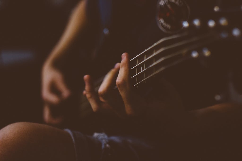 Moody close-up of a hand playing a guitar. Perfect for music-themed projects.